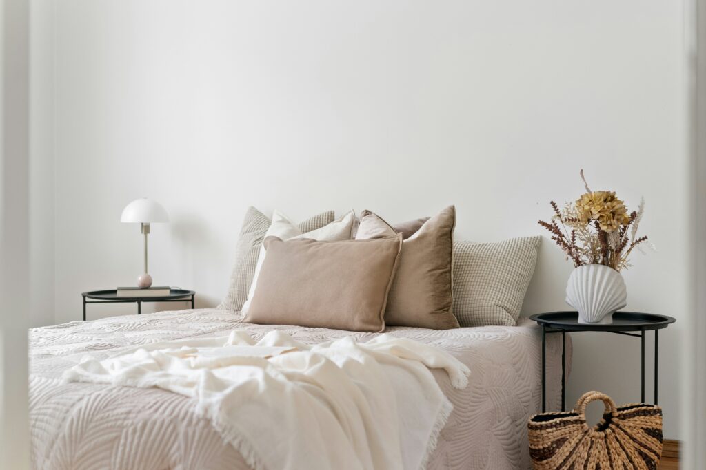 Cama posta com roupa de cama em linho, almofadas em diferentes texturas e manta de tricô