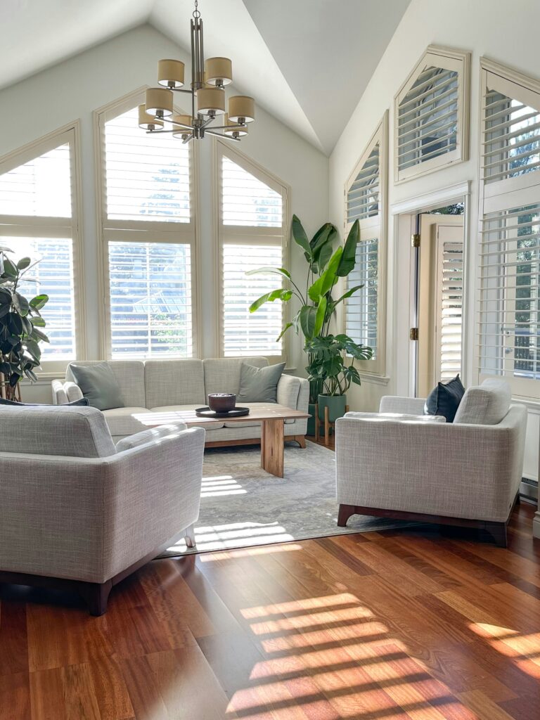 Sala de estar com design biofílico, plantas grandes, móveis de madeira e luz natural