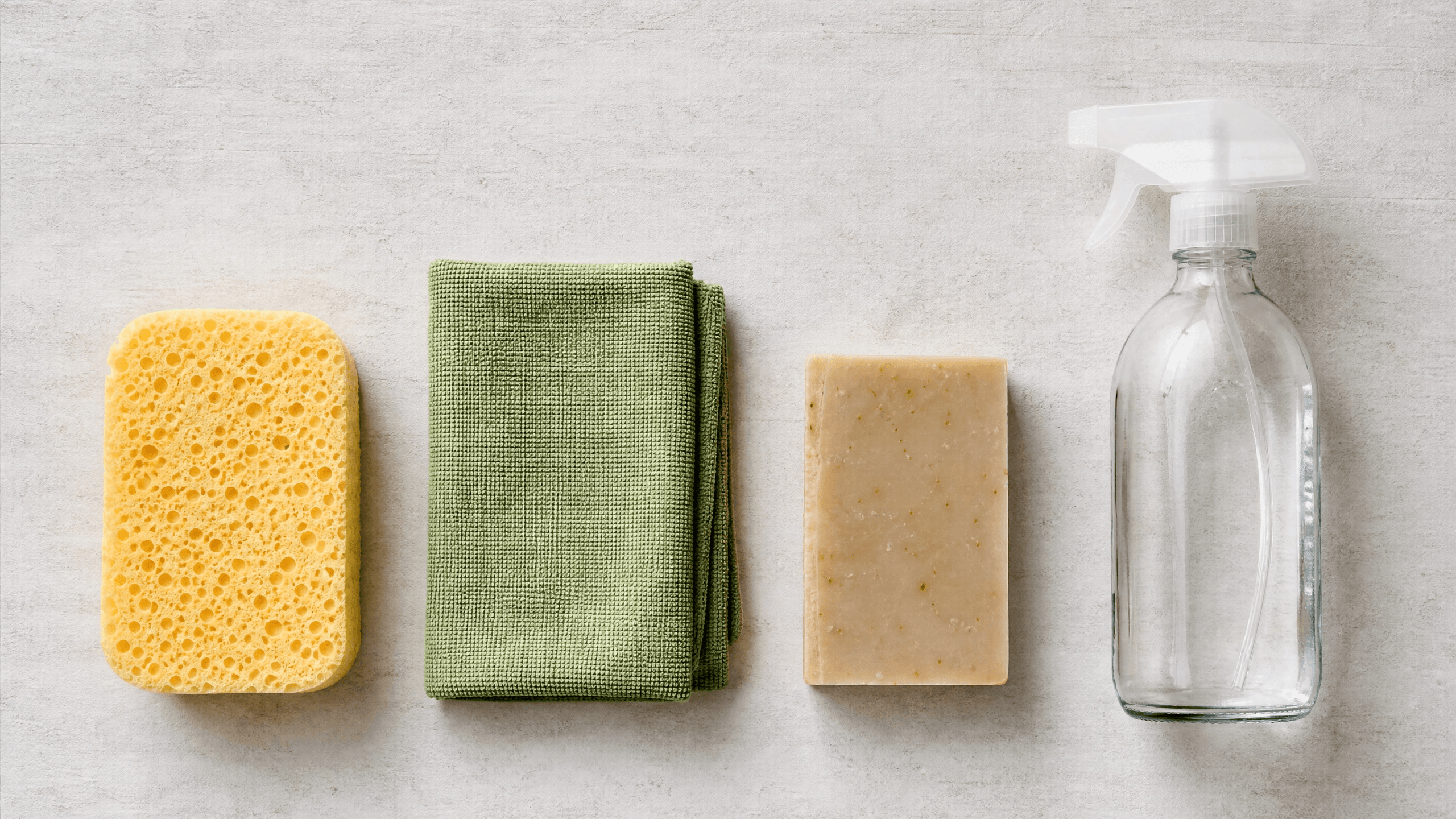 Flat lay com esponja de celulose, pano de microfibra, sabão ecológico e spray reutilizável