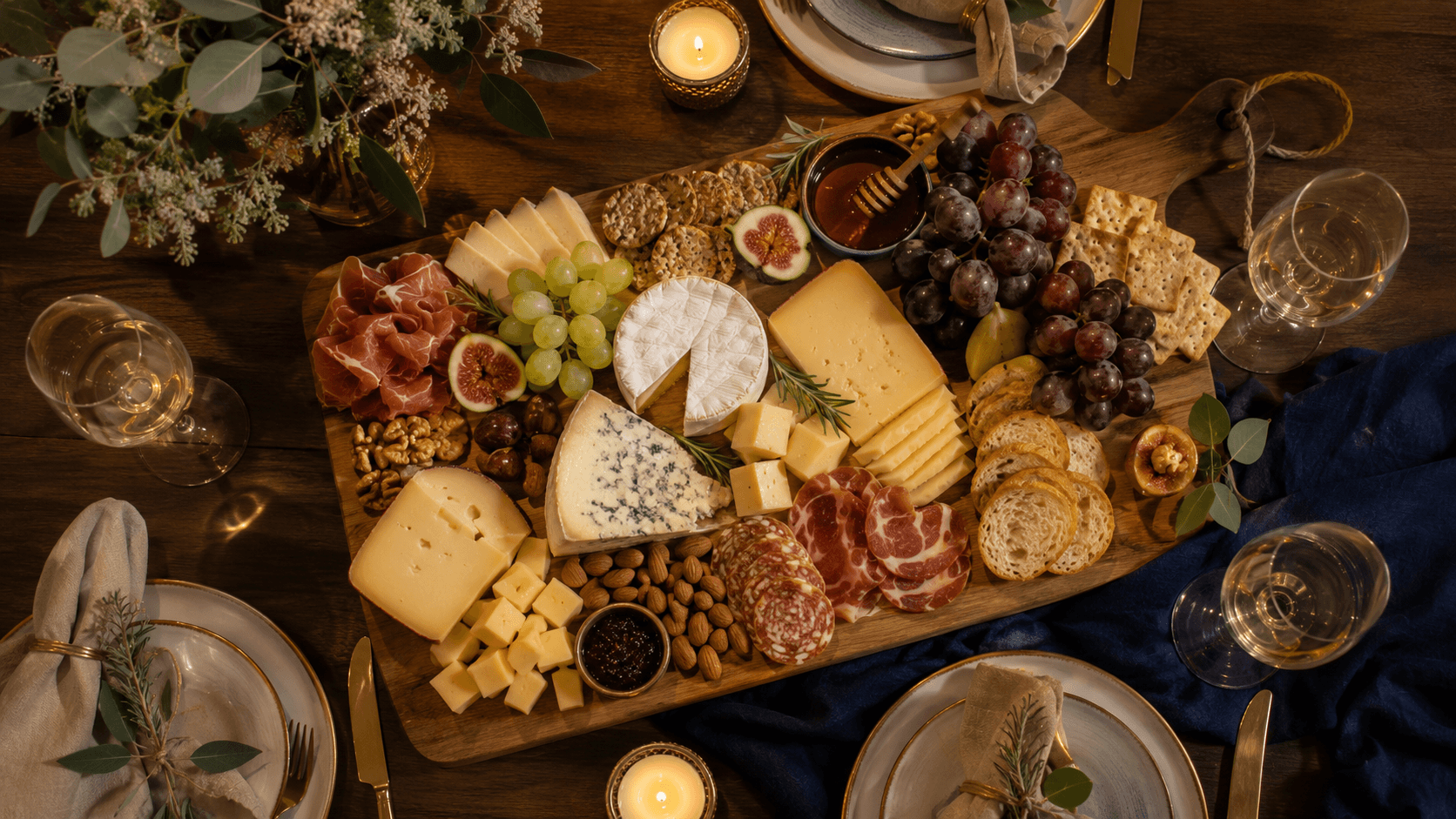 Tábua de queijos e vinhos vista de cima, mesa posta com taças, uvas e guardanapos de linho